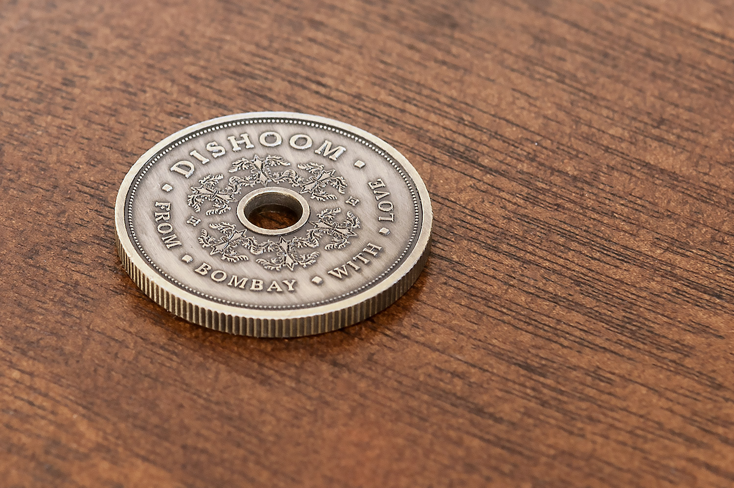 Intricate and detailed bronze coin design for Dishoom, designed by SAINT Design.