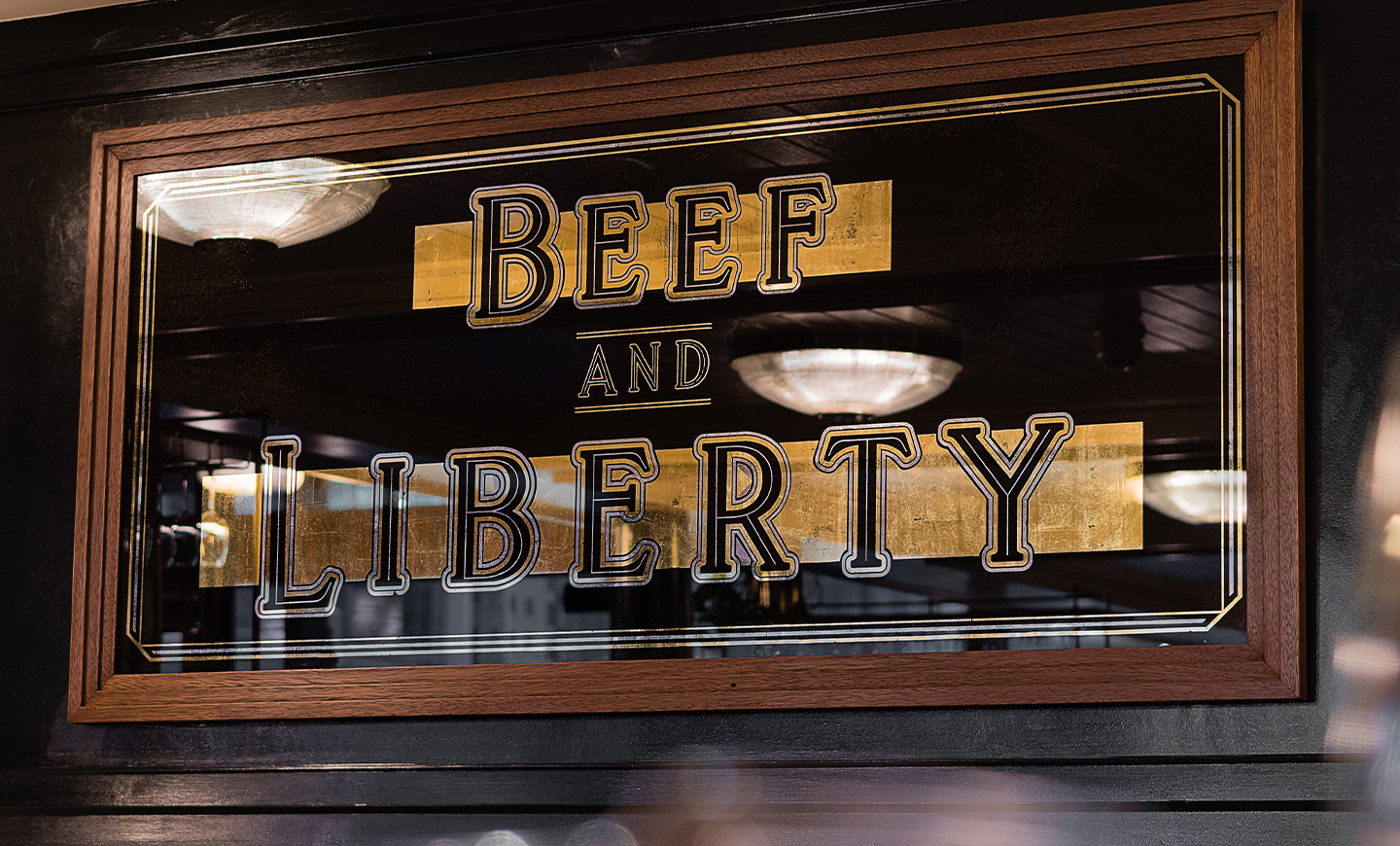 Gold leaf mirror art of the crafted typography stating Beef and Liberty, by SAINT Design for Hawskmoor.
