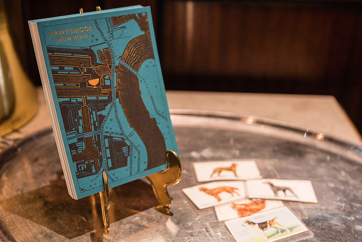 The front of a blue postcard with a map of the Isle of Dogs as a design detail, by SAINT Design for Hawksmoor.